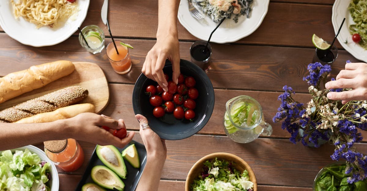 Home A group of people sharing a vibrant meal with salads, pasta, and fresh vegetables, promoting togetherness.